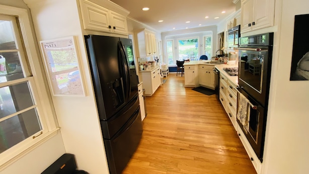 A modern kitchen with white cabinets, a black refrigerator, and an oven. - Family friendly home on quiet street (Atlanta)