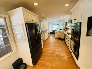A modern kitchen with white cabinets, a black refrigerator, and an oven.