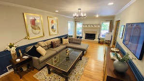 A living room with a sectional sofa, a glass coffee table, and a fireplace. - Family friendly home on quiet street (Atlanta)