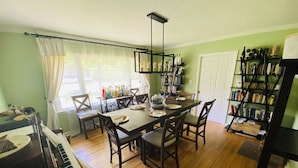 A dining area with a wooden table, chairs, a piano, and bookshelves. - Family friendly home on quiet street (Atlanta)