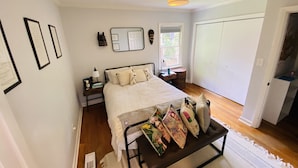 A bedroom with a bed, bedside table, lamp, and a mirror on the wall. - Family friendly home on quiet street (Atlanta)