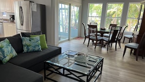 A modern living room with a sofa, coffee table, dining table, and chairs.