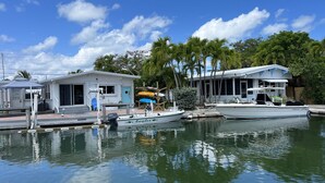 A marina with boats docked, a small house with a porch, and a clear blue sky.