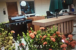 Enjoy al fresco dining and relaxation on this patio, featuring a barbecue grill, planter, and seating area.