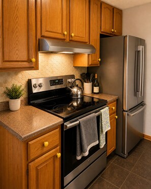 A kitchen with wooden cabinets, a stainless steel stove, and a refrigerator.