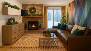 A cozy living room with a fireplace, a sofa, a coffee table, and a Christmas tree.