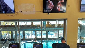 A gym with treadmills, a TV displaying a movie, and a view of an outdoor swimming pool.