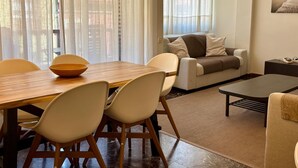 A living room with a wooden dining table, beige chairs, a sofa, and a coffee table. - Modern apartment close to the Camp Nou Stadium (BARCELONA)