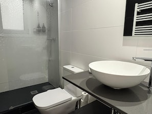 Une salle de bain moderne avec un grand lavabo blanc, des toilettes et une douche.