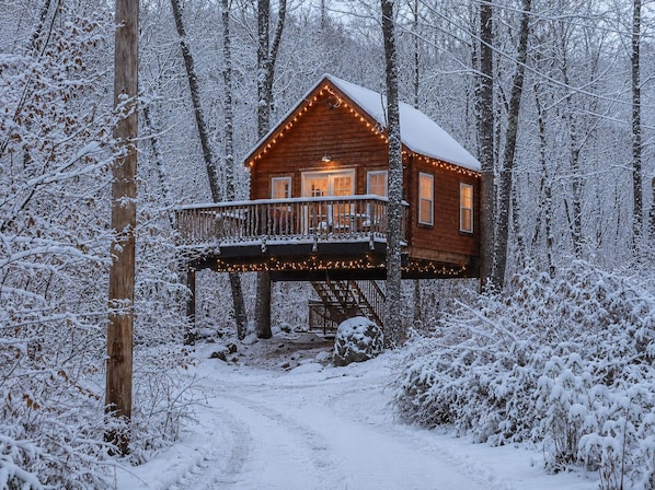 Una cabaña de madera con balcón, rodeada de árboles cubiertos de nieve.