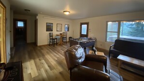 A spacious living room with a foosball table, leather chairs, and a large window with a view of trees. - Black Hills SD Deadwood, Privacy, Comfort & Convenience with Breathtaking Views (Lead)