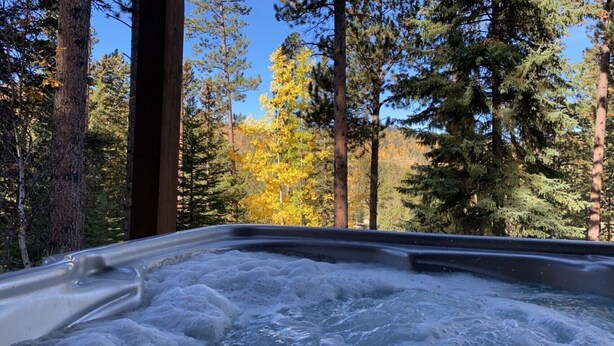 A hot tub surrounded by tall trees and autumn foliage. - Black Hills SD Deadwood, Privacy, Comfort & Convenience with Breathtaking Views (Lead)