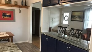A kitchen with dark blue cabinets, a marble countertop, and a dining area with a wooden table and chairs.