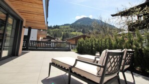 En terrasse med en bænk og et glas vand, med udsigt over et bjergrigt landskab.