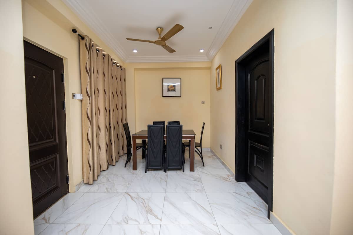 A dining area with a table and chairs, a ceiling fan, and a door with a curtain.