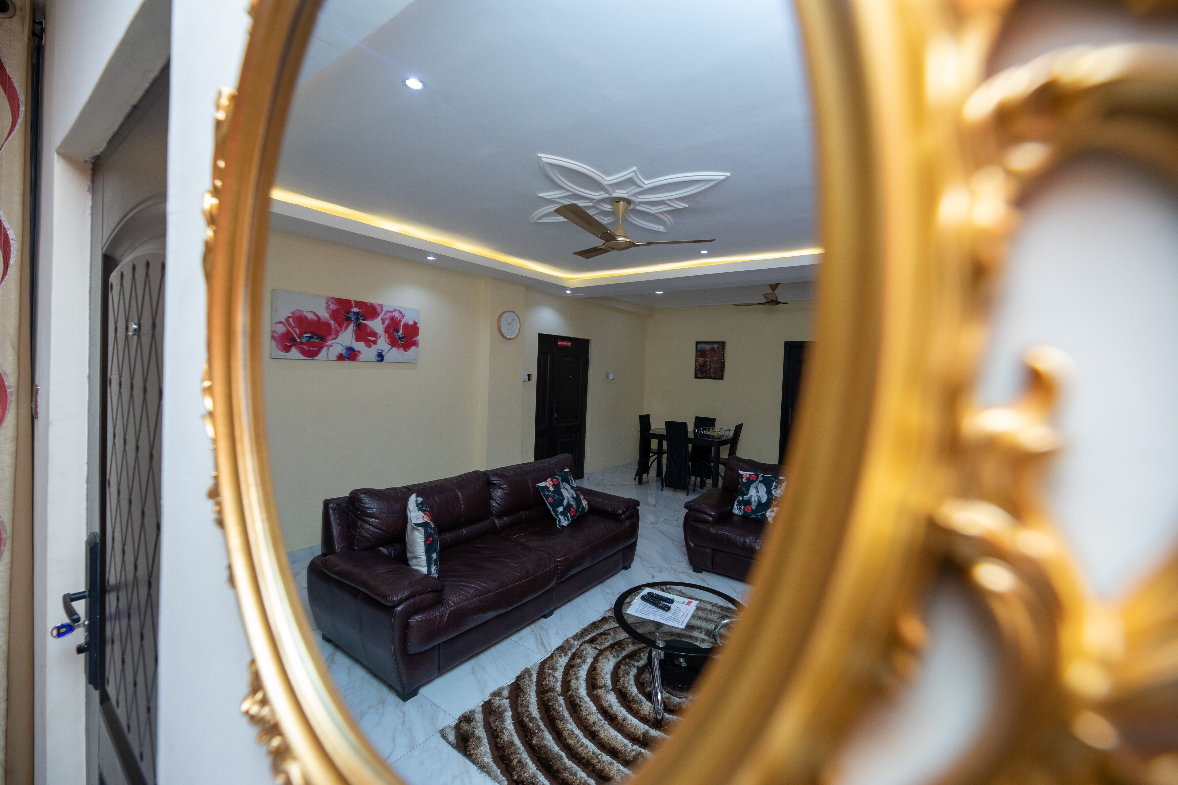 A living room with a brown leather sofa, a coffee table, and a dining area with a table and chairs.