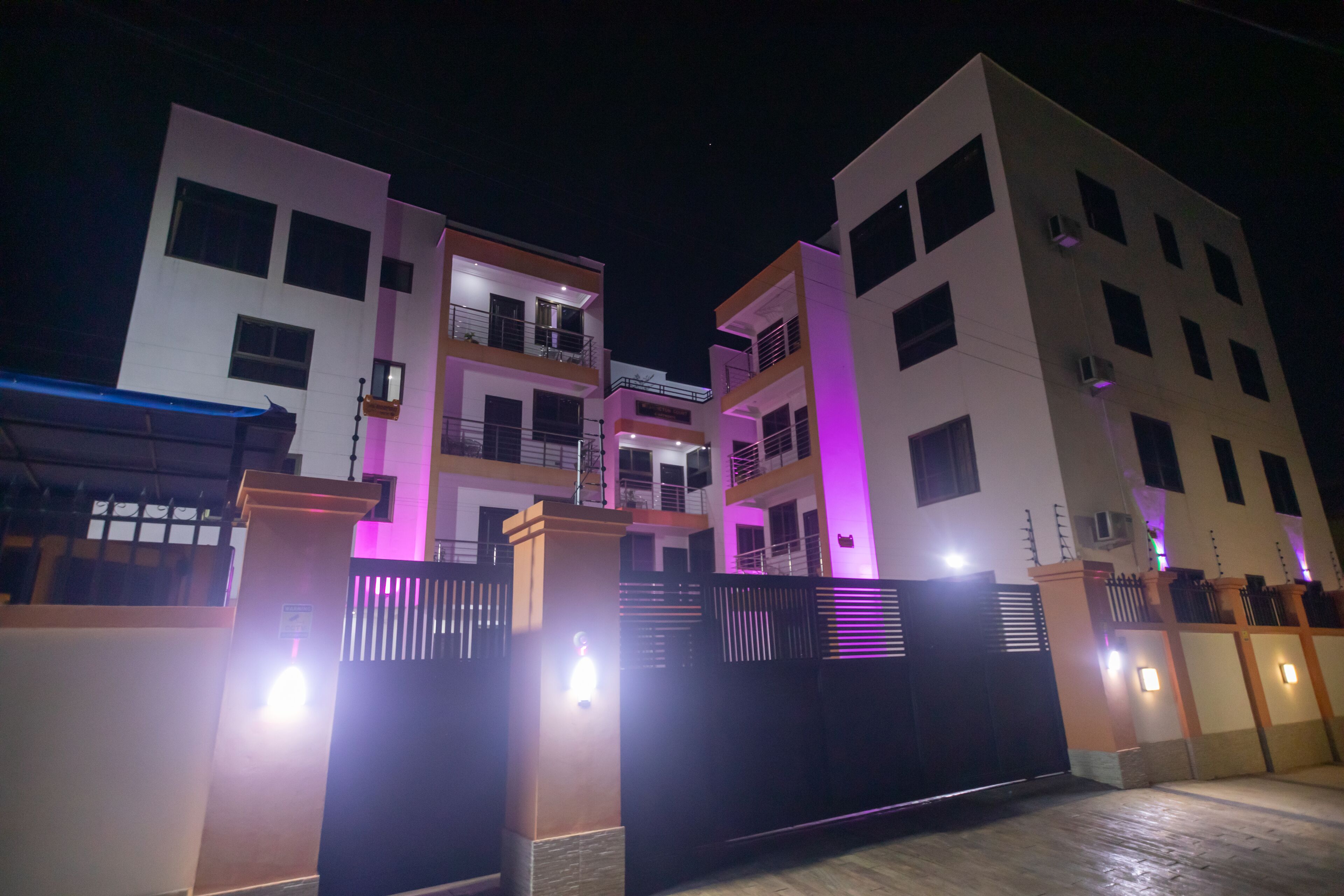 A multi-story residential building with balconies and a gated entrance.