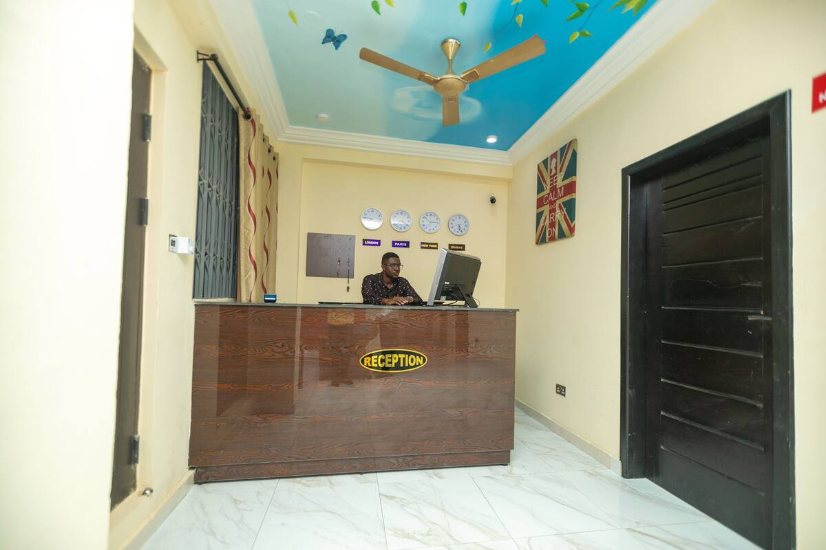 A reception desk with a 'RECEPTION' sign, a ceiling fan, and clocks displaying different time zones.