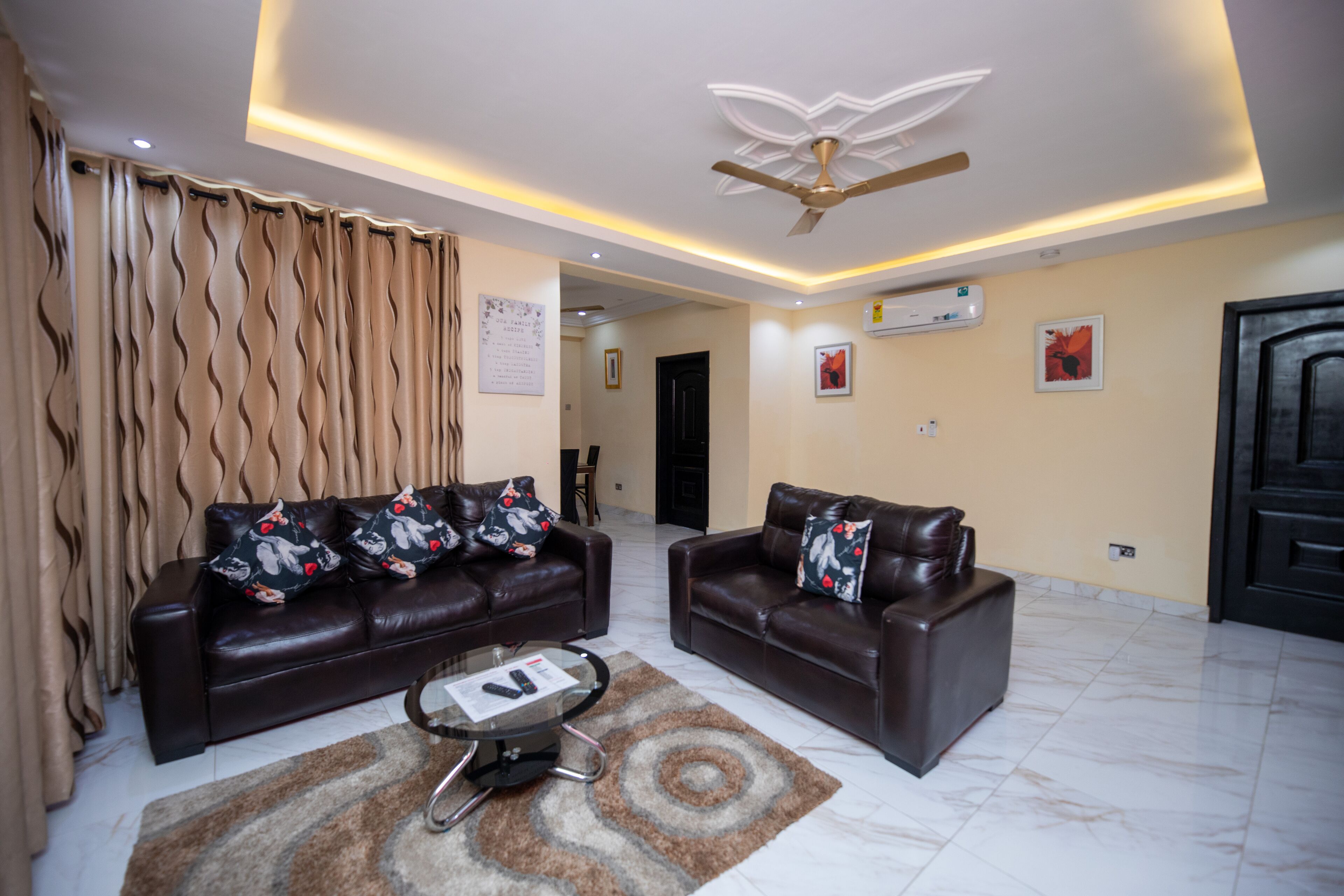 A living room with two leather sofas, a coffee table, and a ceiling fan.