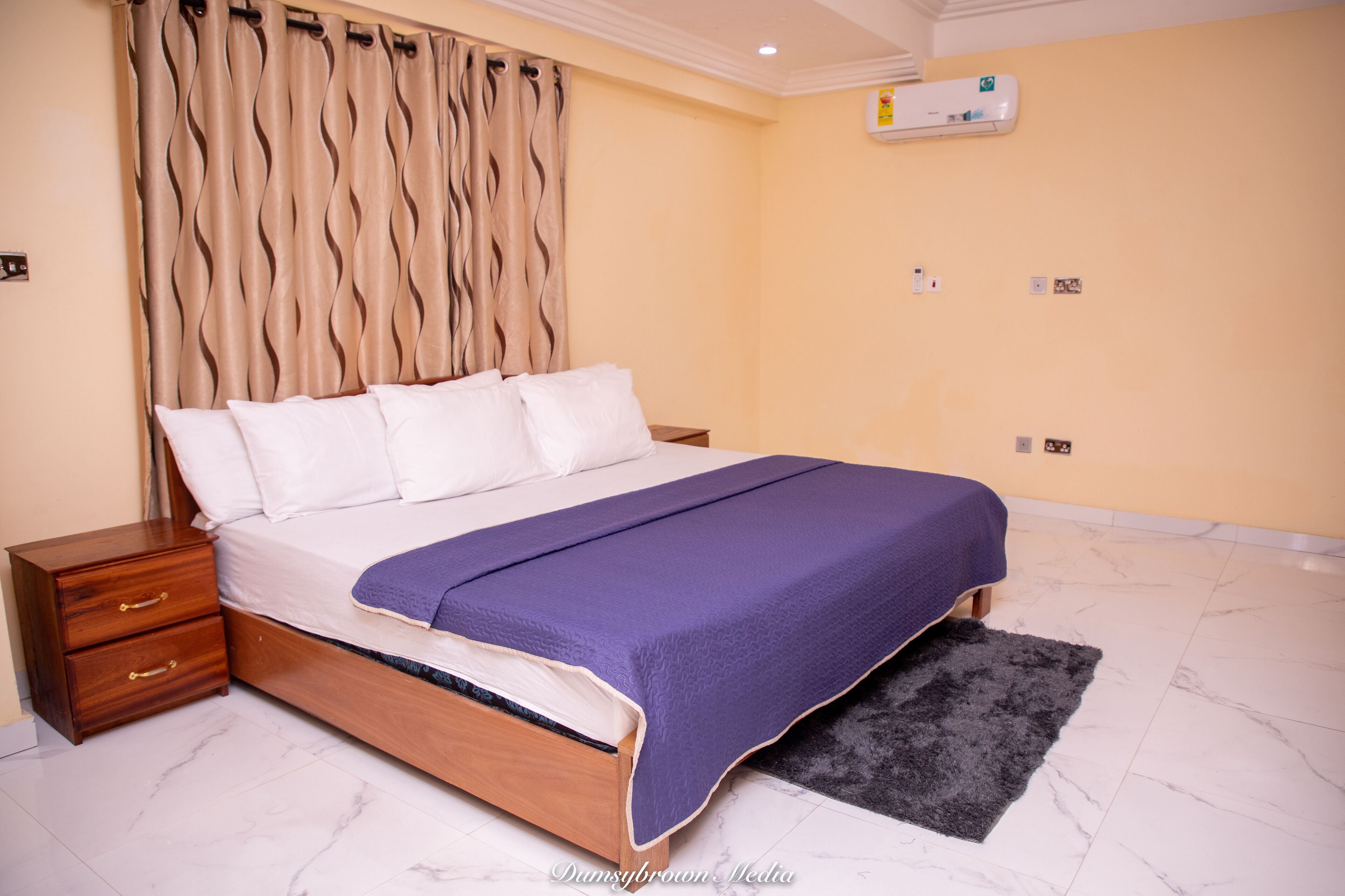 A bedroom with a bed, nightstand, and a wall-mounted air conditioner.