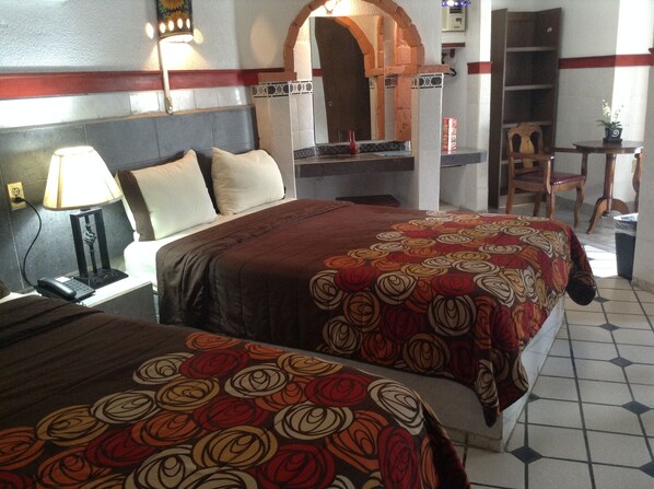 A hotel room with two beds, a nightstand, a lamp, a mirror, and a small table with a chair. - HOTEL TERRANOVA TAMPICO (Tampico)