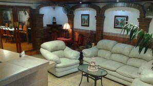 A living room with a sofa, armchairs, and a small table with a cake. There are brick walls and a tiled floor. - HOTEL TERRANOVA TAMPICO (Tampico)