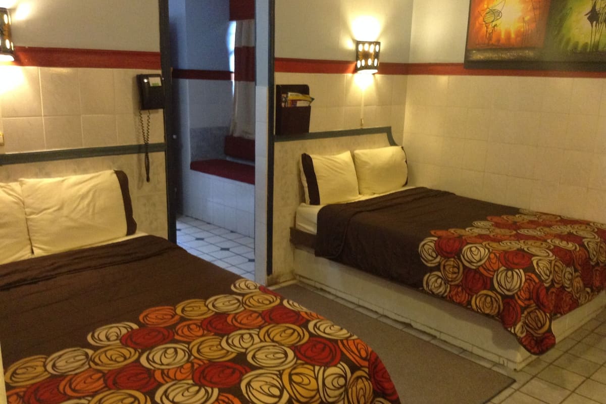 A hotel room with two beds, a bathroom, and a staircase.