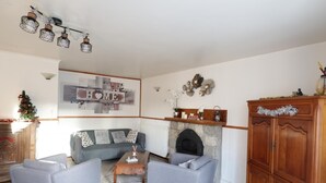 A living room with a grey sofa, two armchairs, a coffee table, a fireplace, and a wooden cabinet. - Tildren - Guern - Gîte (GUERN)
