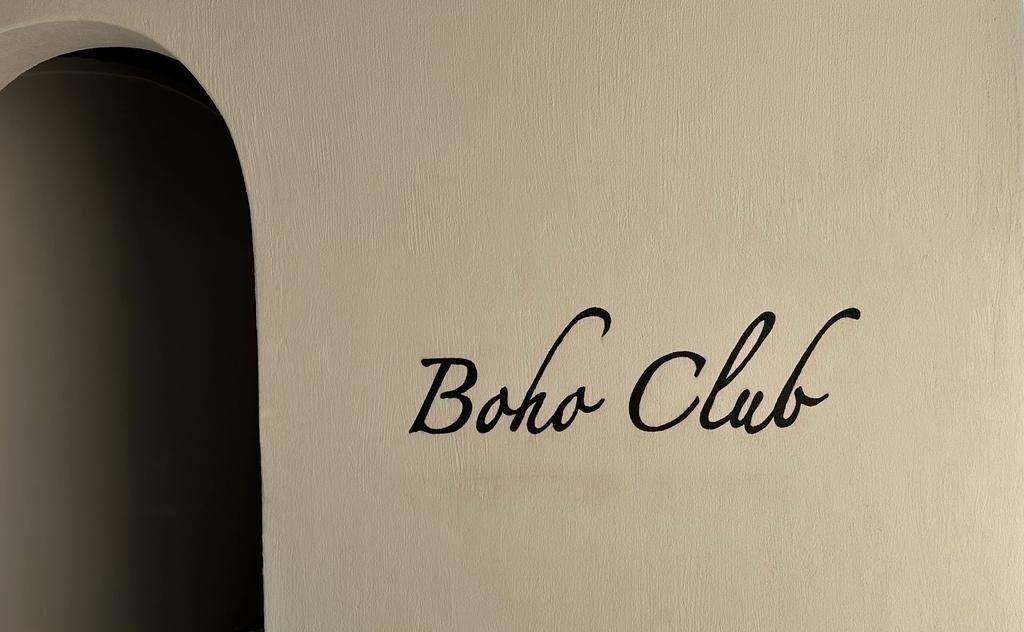 Un muro con la scritta "Boho Club" in caratteri corsivi.