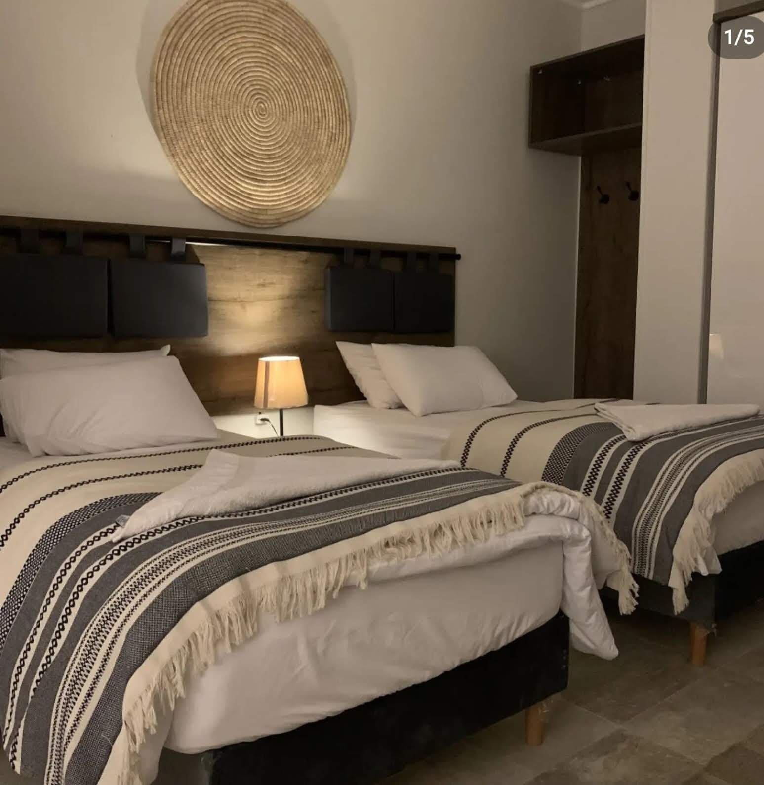 A double bed with a headboard, a bedside table with a lamp, and a circular wall decoration.