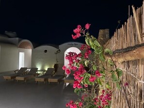 Un hotel con zona de piscina, sillas de descanso y una pared decorativa con un letrero.