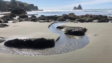Ein Strand mit großen Felsen, sandigem Ufer und freiem Blick auf den Ozean.