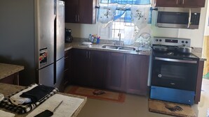 A compact kitchen with a refrigerator, microwave, stove, and sink.
