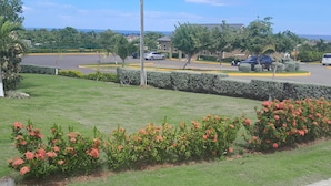 A parking lot with cars, a building, and a grassy area with flowers.