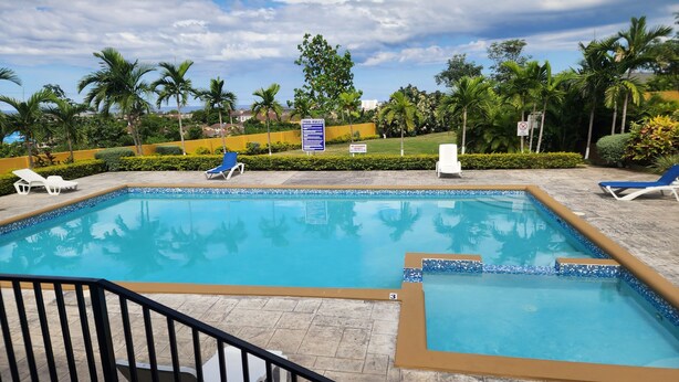 A swimming pool with lounge chairs and a signboard.
