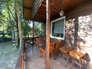 Eine Holzterrasse mit Tisch und Stühlen, umgeben von Bäumen.