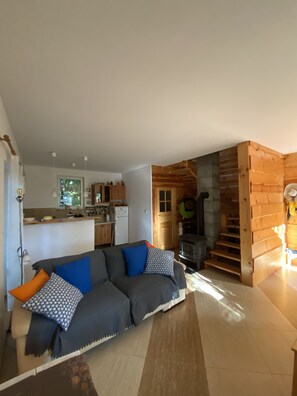 Ein gemütliches Wohnzimmer mit einer Couch, einer Lampe und einer Küche im Hintergrund.