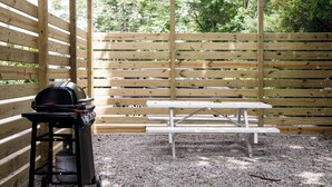 A wooden fence, a barbecue grill, and a picnic table in an outdoor area. - 70's Vibe | Beach | Downtown | AC | Nightlife | (Traverse City)