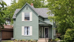 A two-story house with a front porch, a chimney, and a number '624' on the door. - 70's Vibe | Beach | Downtown | AC | Nightlife | (Traverse City)