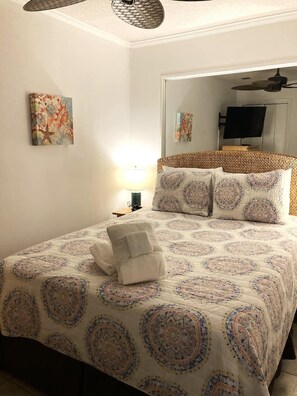 Un lit bien fait, avec une couvre-lit à motifs, un ensemble de serviettes et une lampe sur une table de chevet.