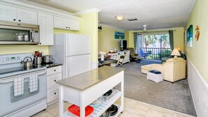 A compact kitchen with modern appliances, a dining area with a sofa and table, and a view of the outdoors through a window. - Condo# 219 Siesta key Paradise unit 219 (Sarasota)