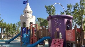 A playground with a castle-like structure, slides, and a purple playhouse.