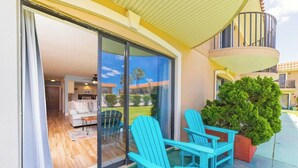 A balcony with turquoise Adirondack chairs, a potted plant, and a view of a residential area. - Seabreeze Escape at Ponce Landing 34 (St. Augustine)
