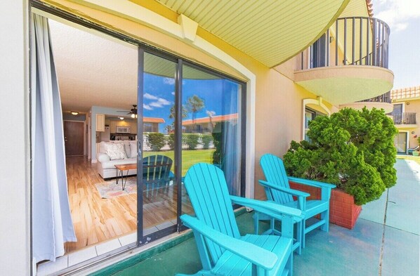 A balcony with turquoise Adirondack chairs, a potted plant, and a view of a residential area. - Seabreeze Escape at Ponce Landing 34 (St. Augustine)