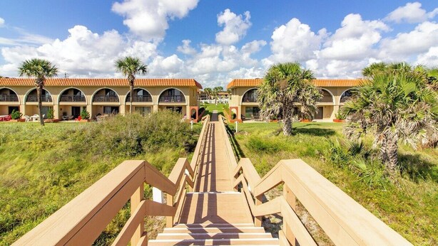 A hotel with a central staircase leading to a building with multiple balconies. - Seabreeze Escape at Ponce Landing 34 (St. Augustine)