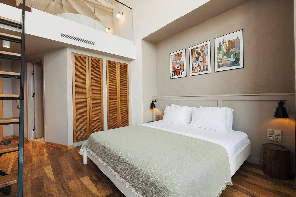 Een slaapkamer met een bed, een houten kledingkast en kunst aan de muur.