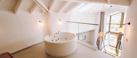Une salle de bain moderne dotée d’une grande baignoire sur pieds, d’une douche à parois de verre et offrant une vue sur l’extérieur grâce à une grande fenêtre.