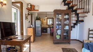 A living room with a television, wooden table, and a cabinet with dishes. - S267 - Sirolo , portion of a single villa surrounded by the greenery of Conero (Sirolo)