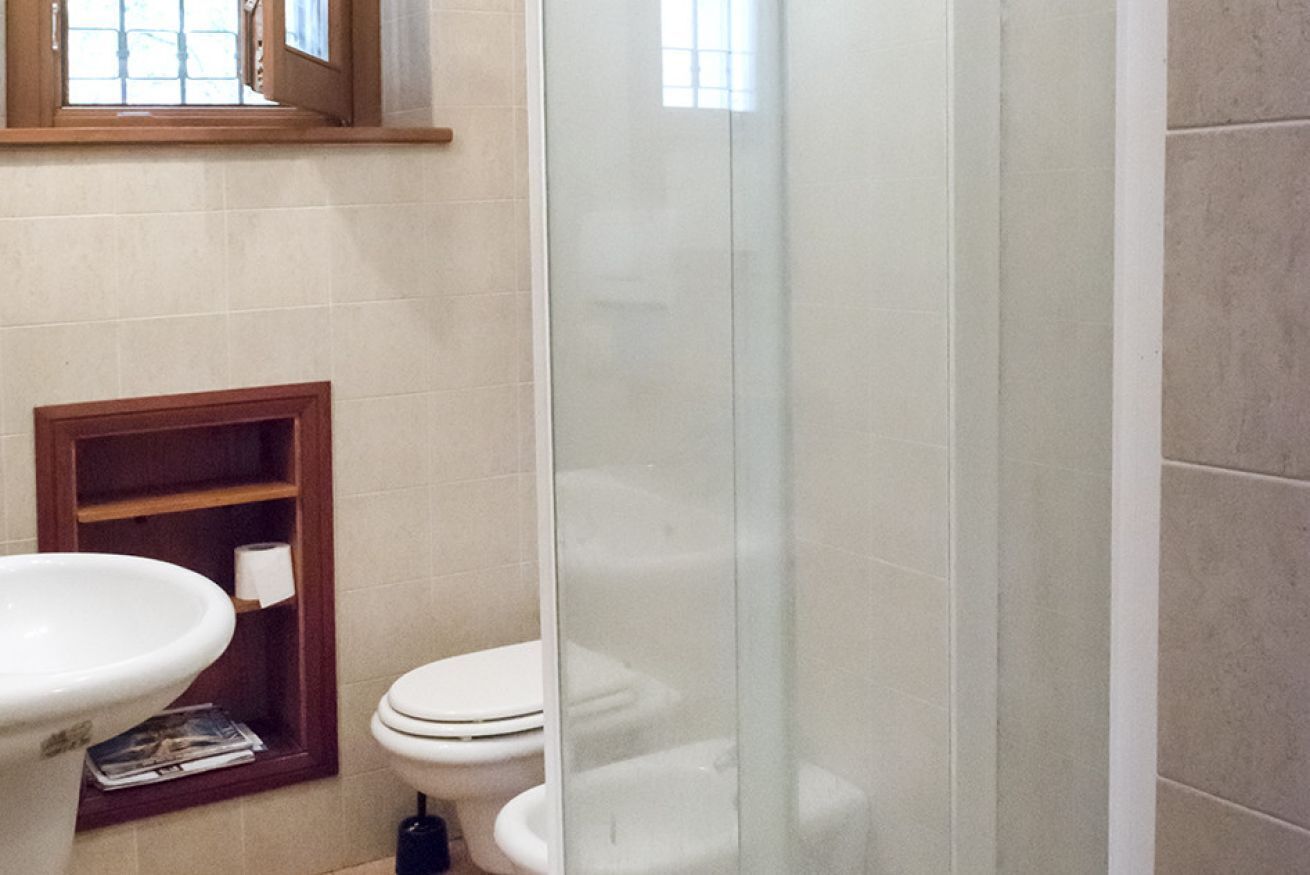 A bathroom with a toilet, a sink, and a glass shower enclosure.