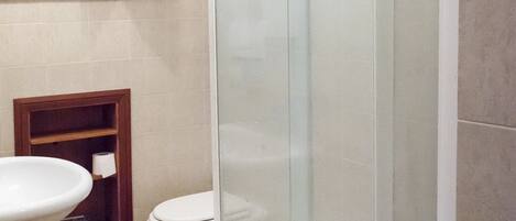 A bathroom with a toilet, a sink, and a glass shower enclosure.